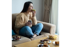Woman on a couch eating sweets.